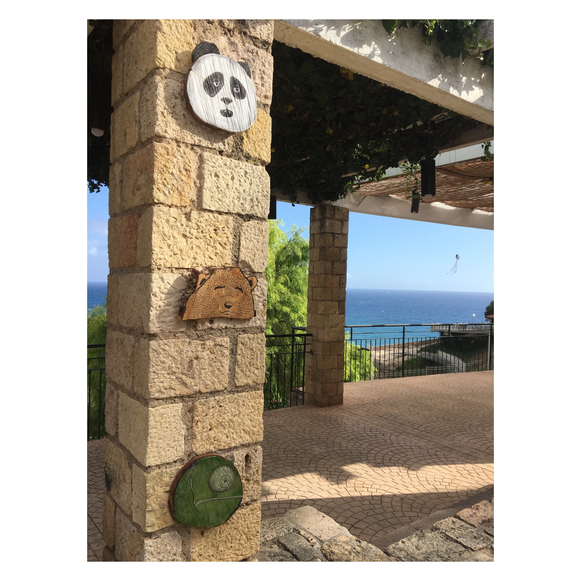 Panda, ós i camaleó pintats sobre fusta en una columna de pedra