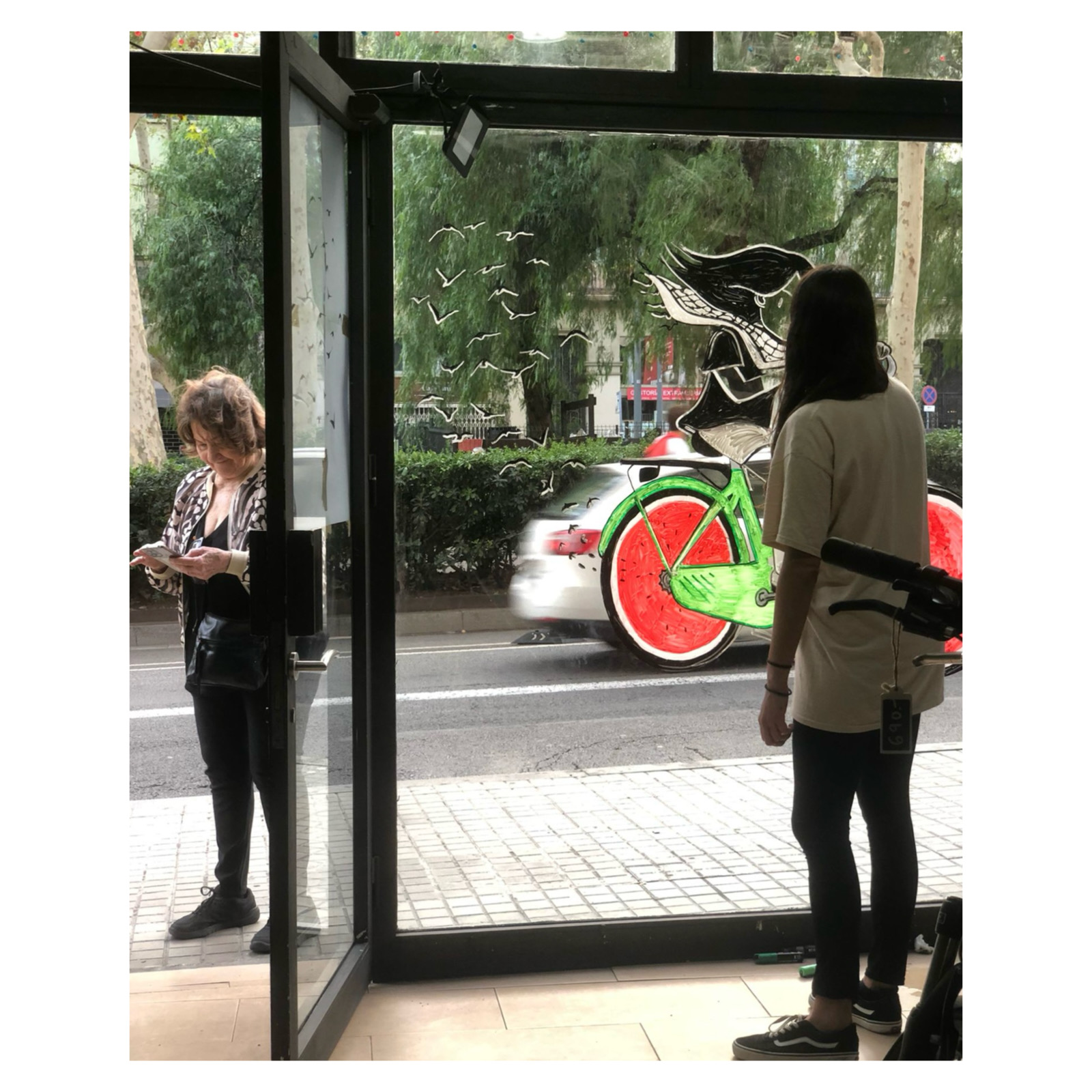 Interior de la Botiga Baik amb la il·lustració al vidre i el carrer al fons