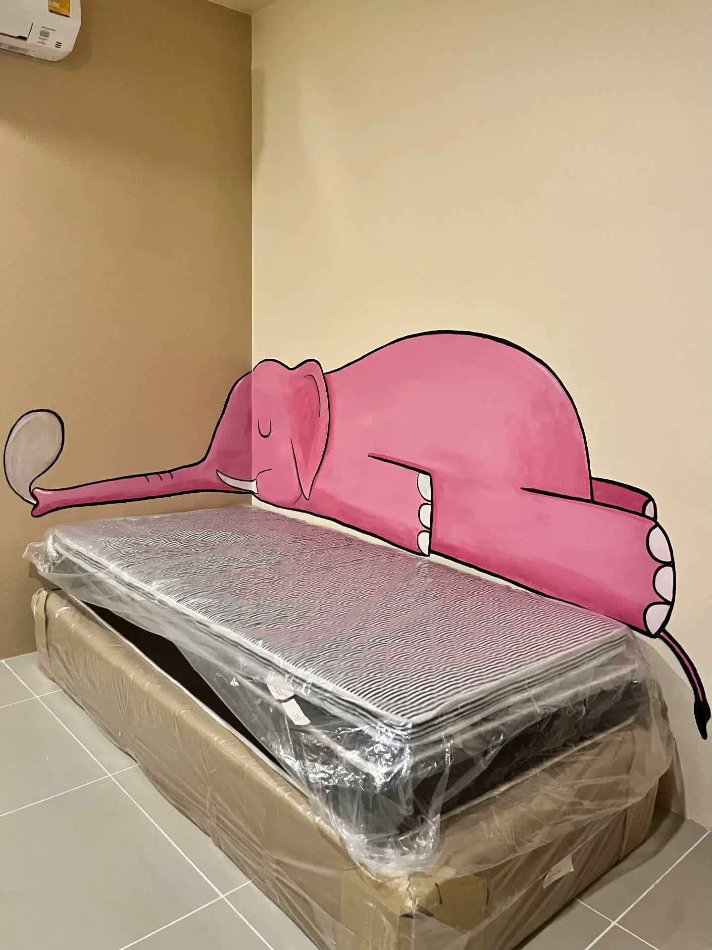 Mural d'un elefant rosa dormint sobre un llit