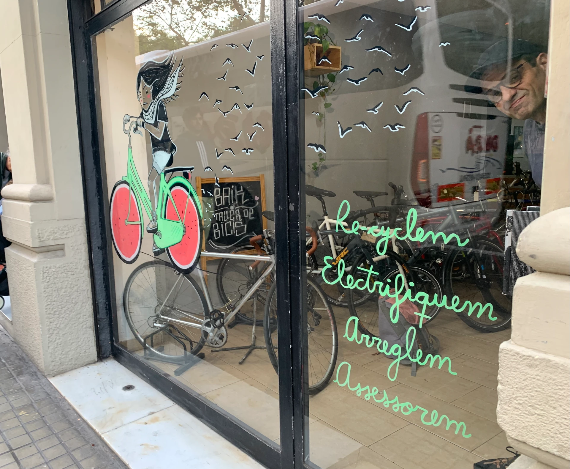 Il·lustració al vidre d'una nena amb bicicleta de rodanxes de síndria a la Botiga Baik